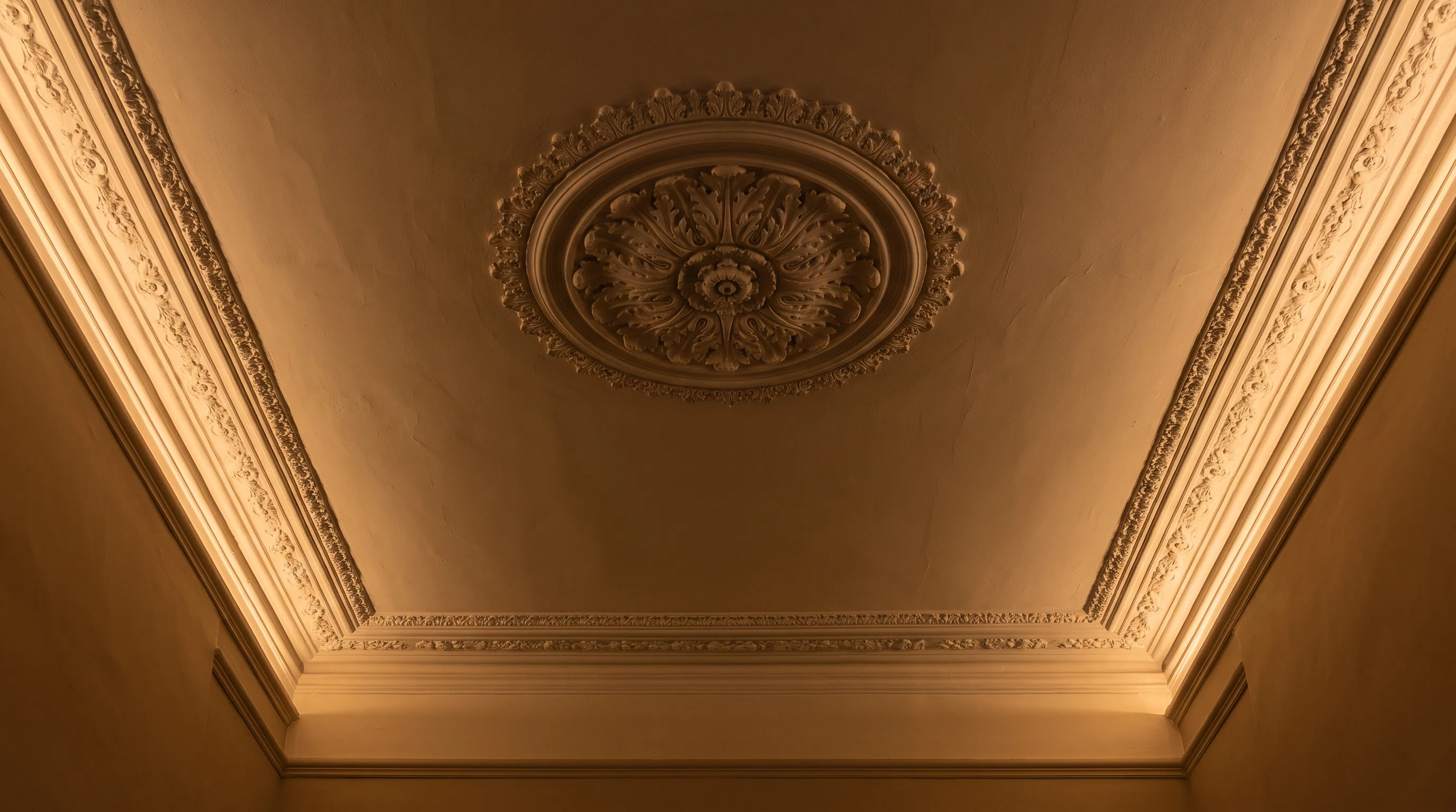 Warm new lighting grazing the cornice of a period ceiling, the original plaster rose retained
