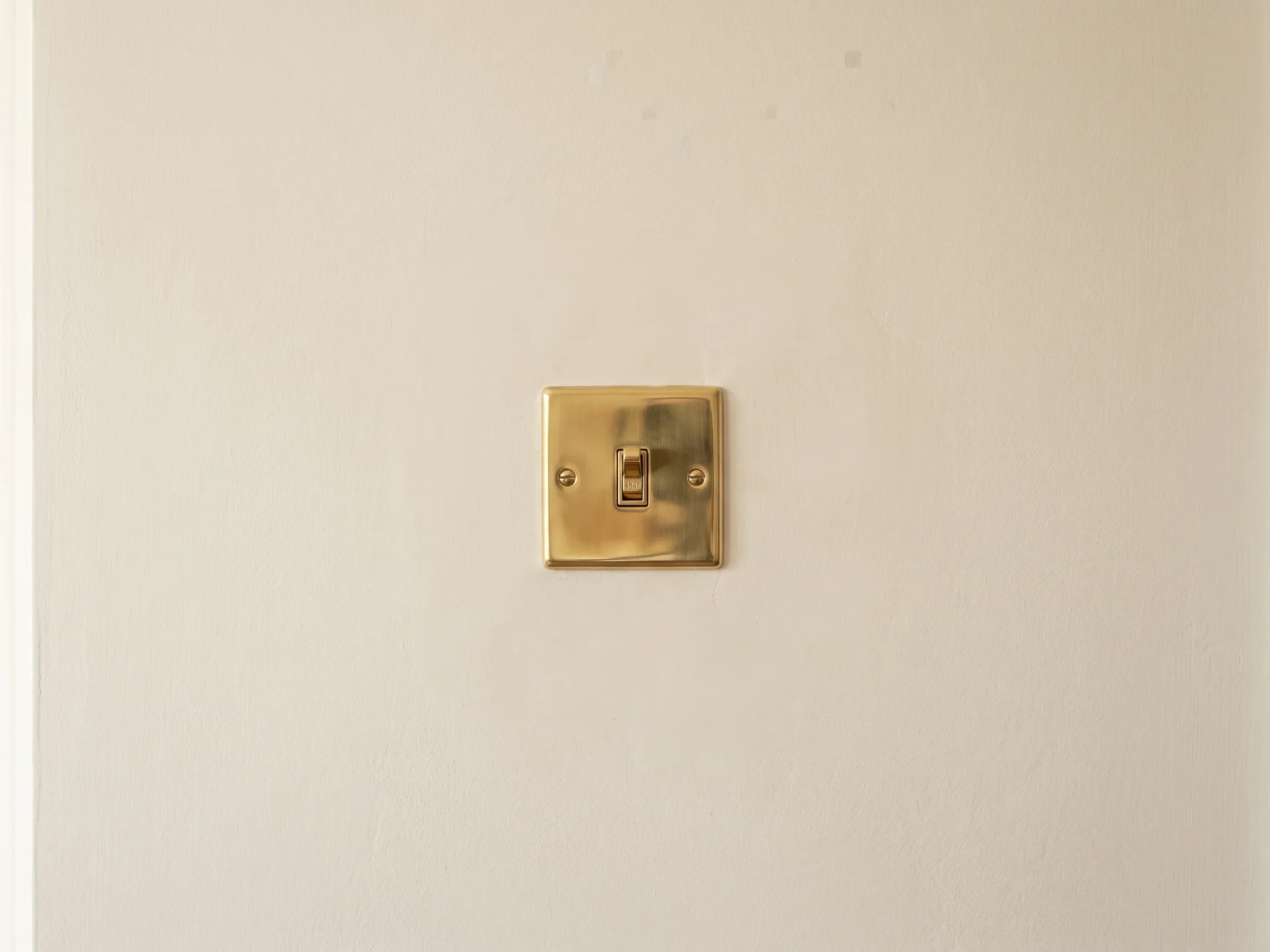 The wall made good and painted, with a brass toggle switch fitted square to the finished plaster